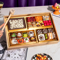 Small Halloween dessert board with assorted chocolate truffles, brownie bites, and candy in a gold-lined wooden tray, featuring a 