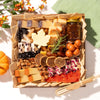 autumn-themed charcuterie board featuring cheeses, figs, nuts, a maple leaf-shaped cheese, & seasonal accents on a white background