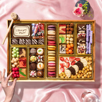 Assorted chocolates in a wooden box on a pink fabric background