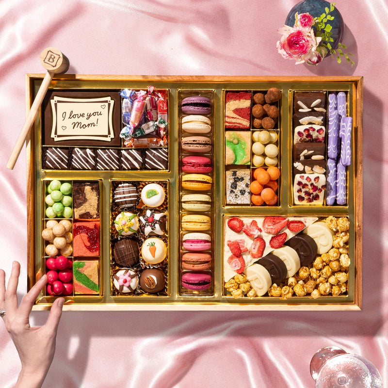Assorted chocolates in a wooden box on a pink fabric background