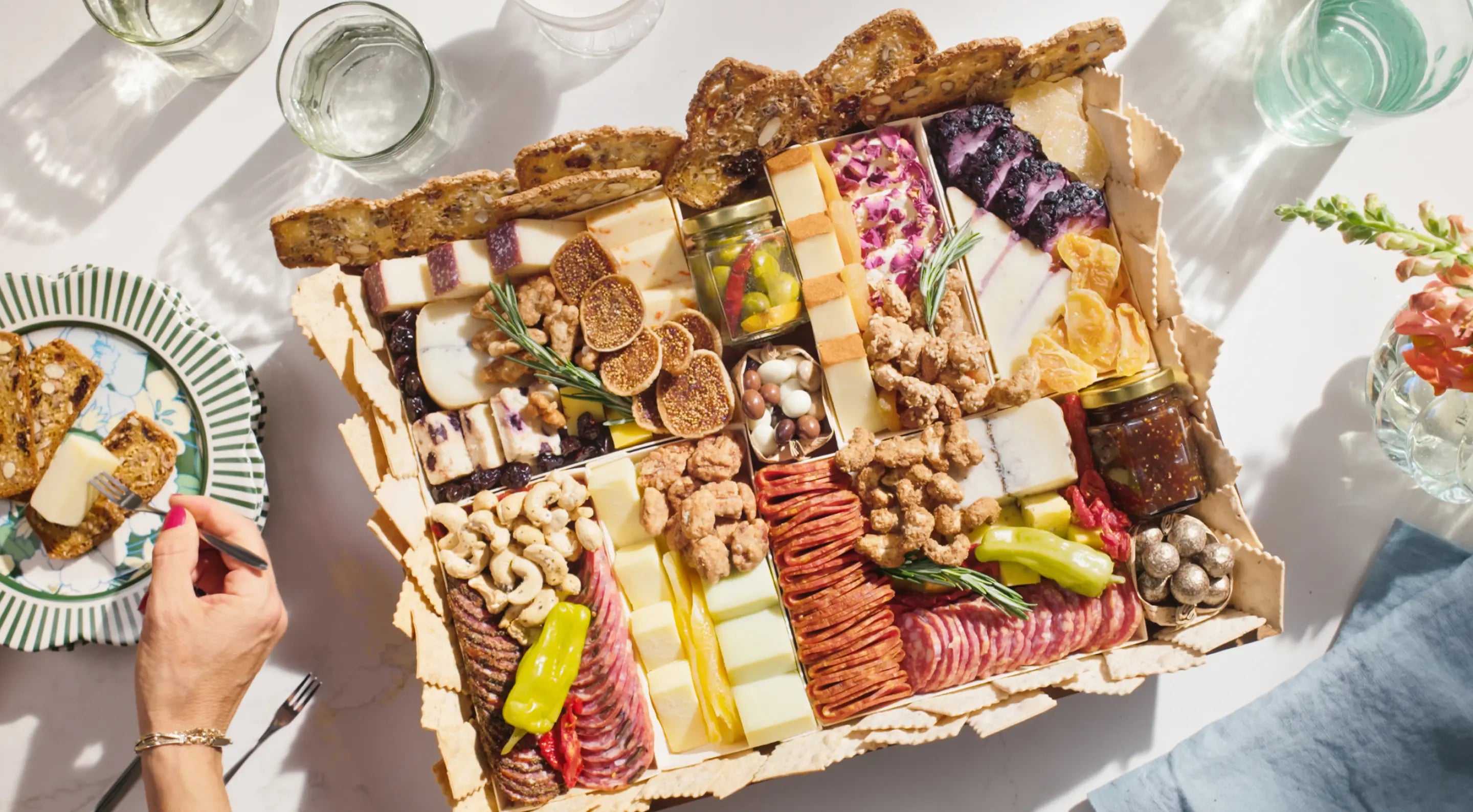 Charcuterie board with assorted cheeses, meats, nuts, and dried fruits, served alongside crackers and a decorative plate.