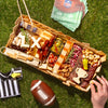 Super Bowl charcuterie board featuring cheeses, meats, crackers, nuts, and football-themed cheese cutouts on a picnic setting.