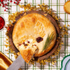 Holiday baked brie topped with cranberries on a festive table with gold and red decorations.