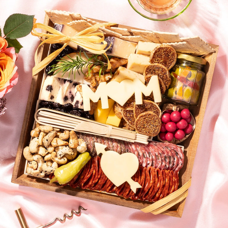 small Mother's Day charcuterie board arranged for a special occasion with cheeses, meats, nuts, & decorative "MOM" & "Heart with Arrow" cheese cutouts