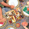 Charcuterie board with "17" in cheese, surrounded by people holding wine glasses at an outdoor celebration table.