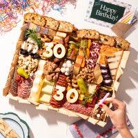 Birthday charcuterie board featuring an assortment of meats, cheeses, nuts, and fruit, with 