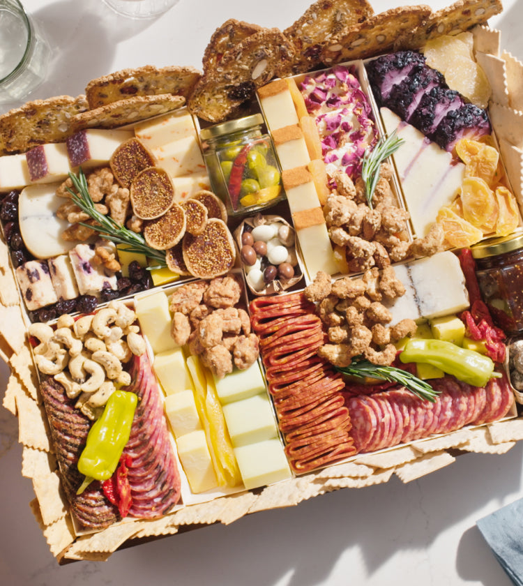 Close-up of a charcuterie board with assorted cheeses, meats, nuts, figs, and crackers, arranged neatly.