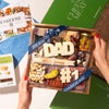 Gift box with 'DAD' and '#1' text, surrounded by Boarderie branding materials.