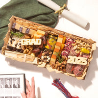 Charcuterie board grad party spread with gourmet meats, cheeses, and festive cheese cutouts reading “GRAD” and “2025.”