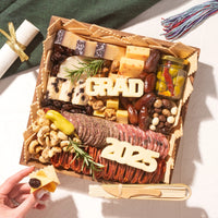 Graduation party charcuterie board with assorted meats, cheeses, nuts, and cheese cutouts reading “GRAD” and “2025.”