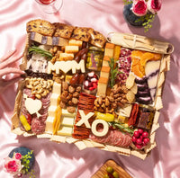 Large Mother's Day charcuterie board with meats, cheeses, dried fruits, nuts, and 