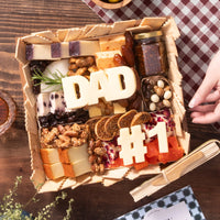 Father's Day cheese board featuring “DAD” and “#1” shaped cheeses, assorted artisanal cheeses, nuts, dried figs, crackers, chocolate-covered treats, and jam in a gift box presentation.