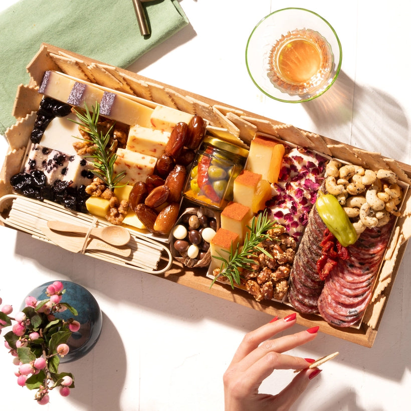 A classic medium charcuterie board gift featuring assorted cheeses, cured meats, nuts, crackers, dates, & olives