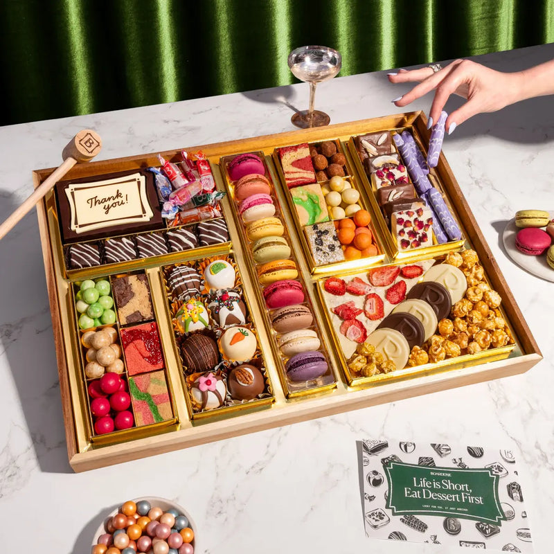 Thank You dessert board with macarons, truffles, brownies, and chocolates on acacia wood.