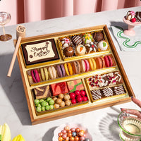 Medium Easter dessert board loaded with two rows of colorful macarons, decorated chocolate truffles, a 