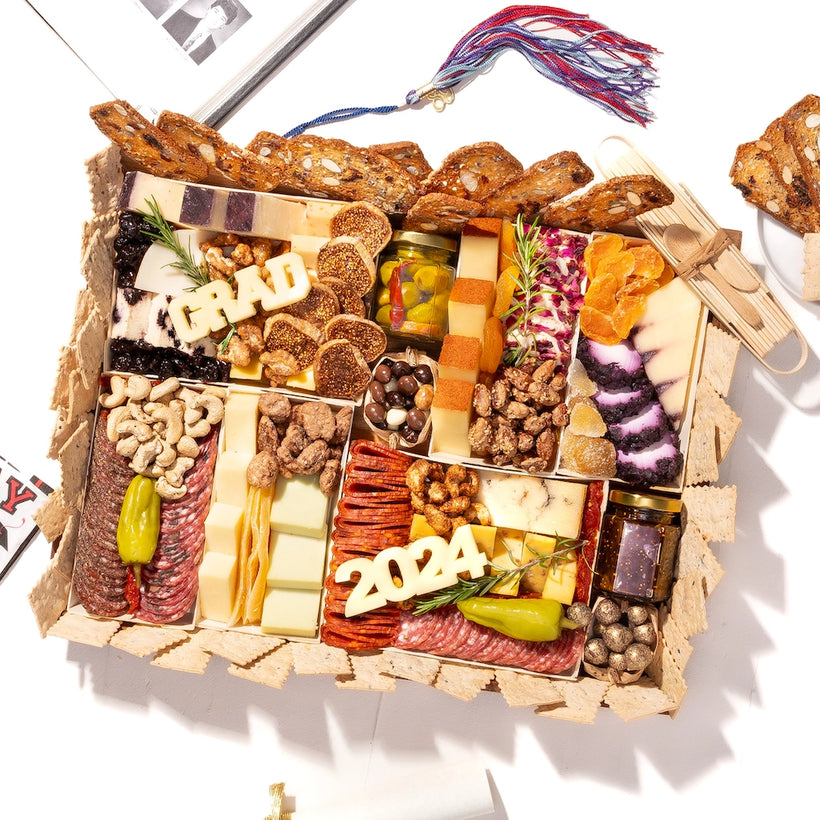 Graduation-themed charcuterie board featuring cheese blocks spelling "GRAD" and "2024," surrounded by crackers and assorted snacks.