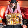 Person in a top hat and pink sequin jacket presenting a Halloween-themed charcuterie board with spooky decorations.