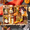 Halloween-themed charcuterie board featuring festive cheeses shaped like a pumpkin and bat, surrounded by assorted snacks and decorations.