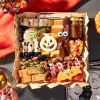 Halloween-themed cheese board with festive cheese shapes, figs, candy corn, nuts, and a small jar of fig jam, arranged without any meats