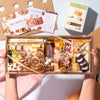 Hands holding a medium charcuterie gift box filled with assorted cheeses, nuts, dried fruits, & crackers, tied with a gold ribbon