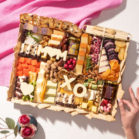 Mother's Day cheese board with assorted cheeses, dried fruits, nuts, and 