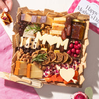 Small Mother's Day cheese board with assorted cheeses, dried fruits, nuts, and 
