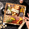 Classic New Years charcuterie gift board with assorted cheeses, cured salami, nuts, olives, jam, 2026 number decoration, and rosemary sprigs.