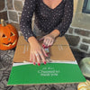 Unboxing of a Halloween-themed charcuterie board with jack-o'-lantern cheese cutout, googly-eyed candy treats, cured meats, nuts, olives and more.