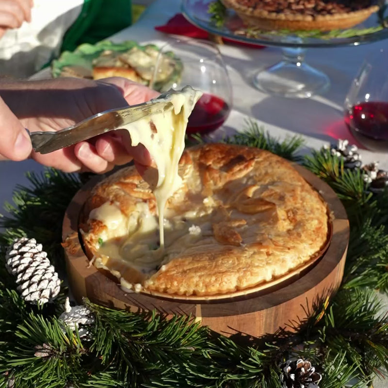 baked brie large round being cut open and enjoyed