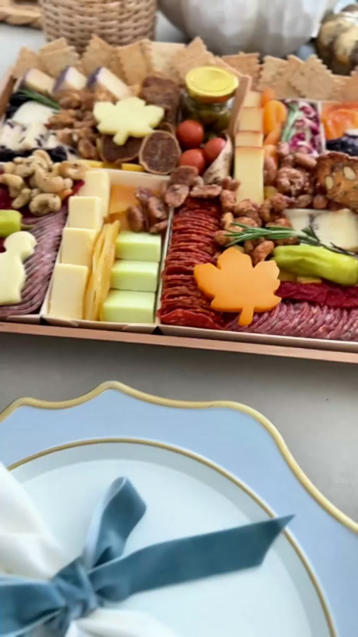 Thanksgiving cheese and charcuterie board close up with meats, nuts, crackers, turkey cut out on a table.