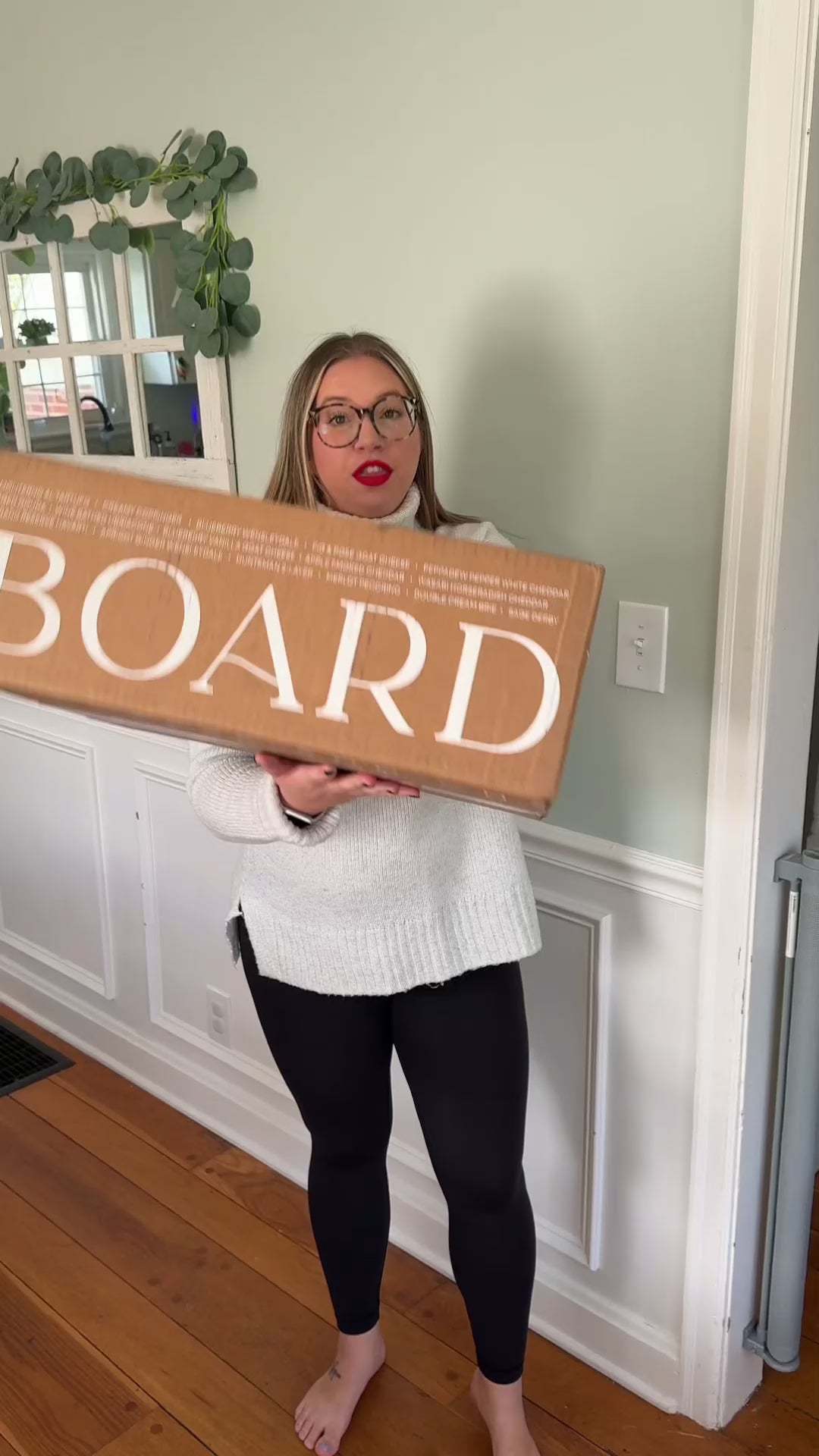 Woman unboxing a Boarderie holiday charcuterie board inside a home with holiday decor.