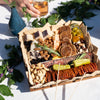 Close-up of a charcuterie board with meats, cheeses, nuts, and crackers on an outdoor table.