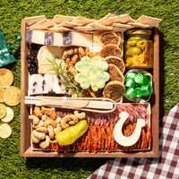 St. Patrick’s Day charcuterie board with gourmet cheeses, meats, nuts, figs, pickles, and cheese cutouts shaped like a shamrock and horseshoe.