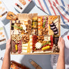 summer-themed charcuterie board with cheeses, meats, nuts, dried fruits, & crackers, held by hands on a table