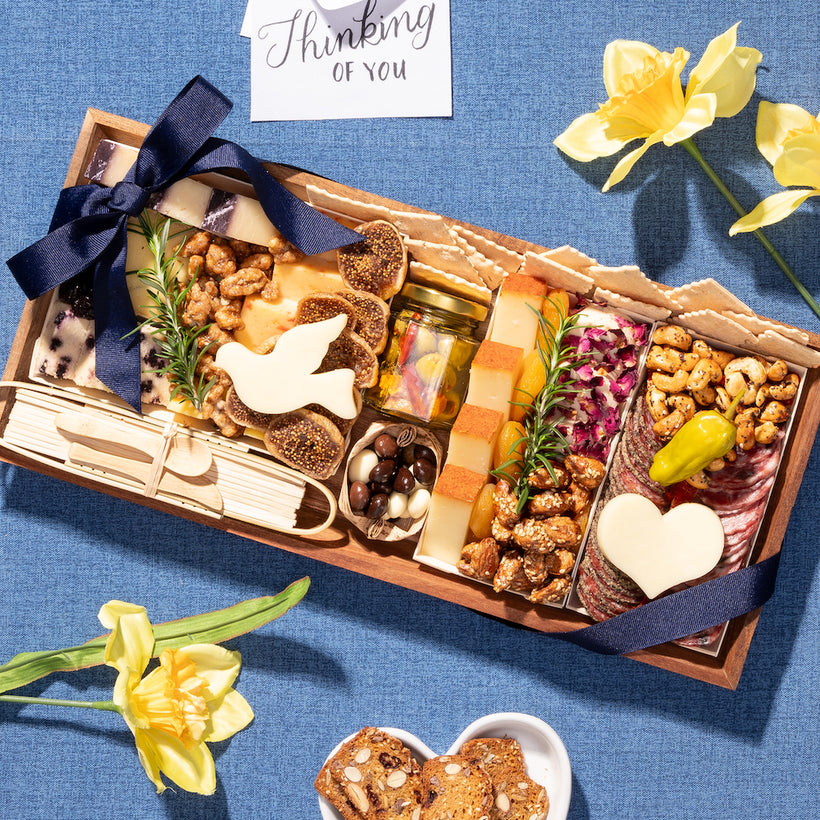 Sympathy charcuterie board with a dove-shaped cheese, nuts, & meats, arranged with a “thinking of you” card & flowers