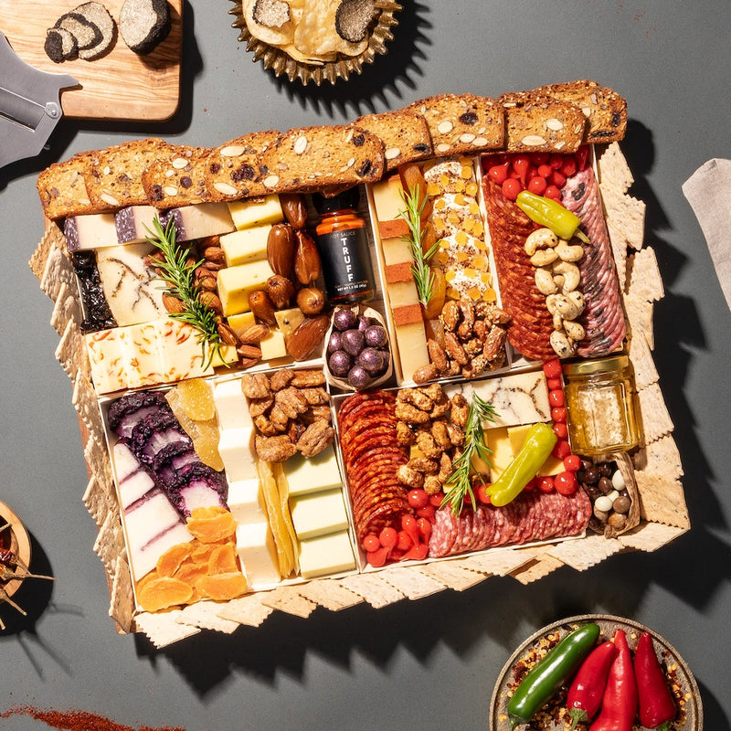 luxurious truffle charcuterie board gift featuring an array of cheeses, cured meats, crackers, nuts, dried fruits, & truffle accents