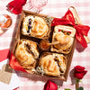 Valentine's baked brie board with decorated pastries, a red bow, fig jam, and romantic red roses.