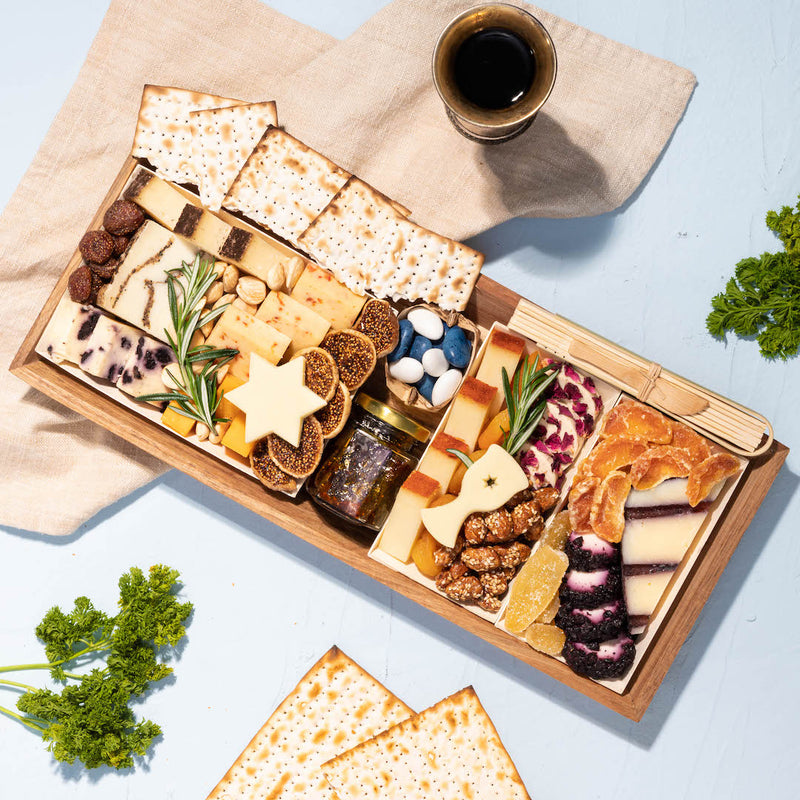 medium wooden charcuterie board featuring an assortment of cheeses, crackers, dried fruits, nuts, and a small jar of jam