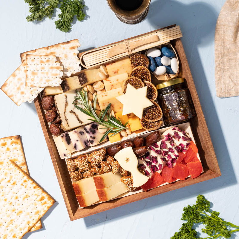 charcuterie board featuring assorted cheeses, crackers, dried fruits, nuts, and a small jar of jam.